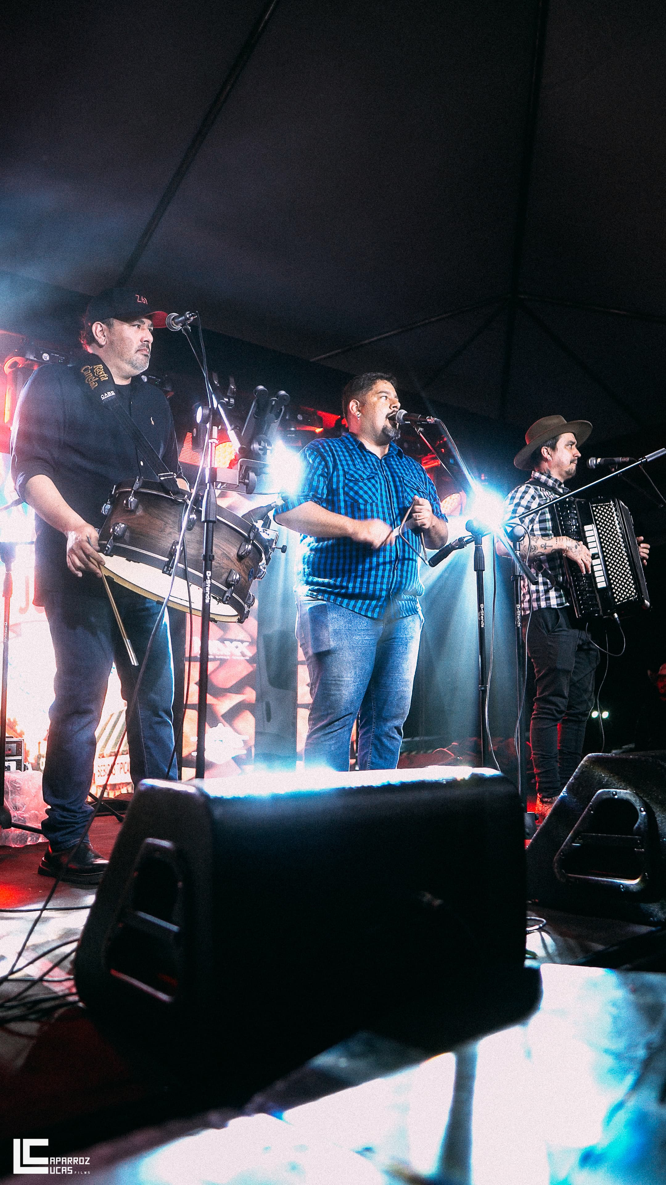 Rasta Canela em show, os três integrantes no palco sob luz quente