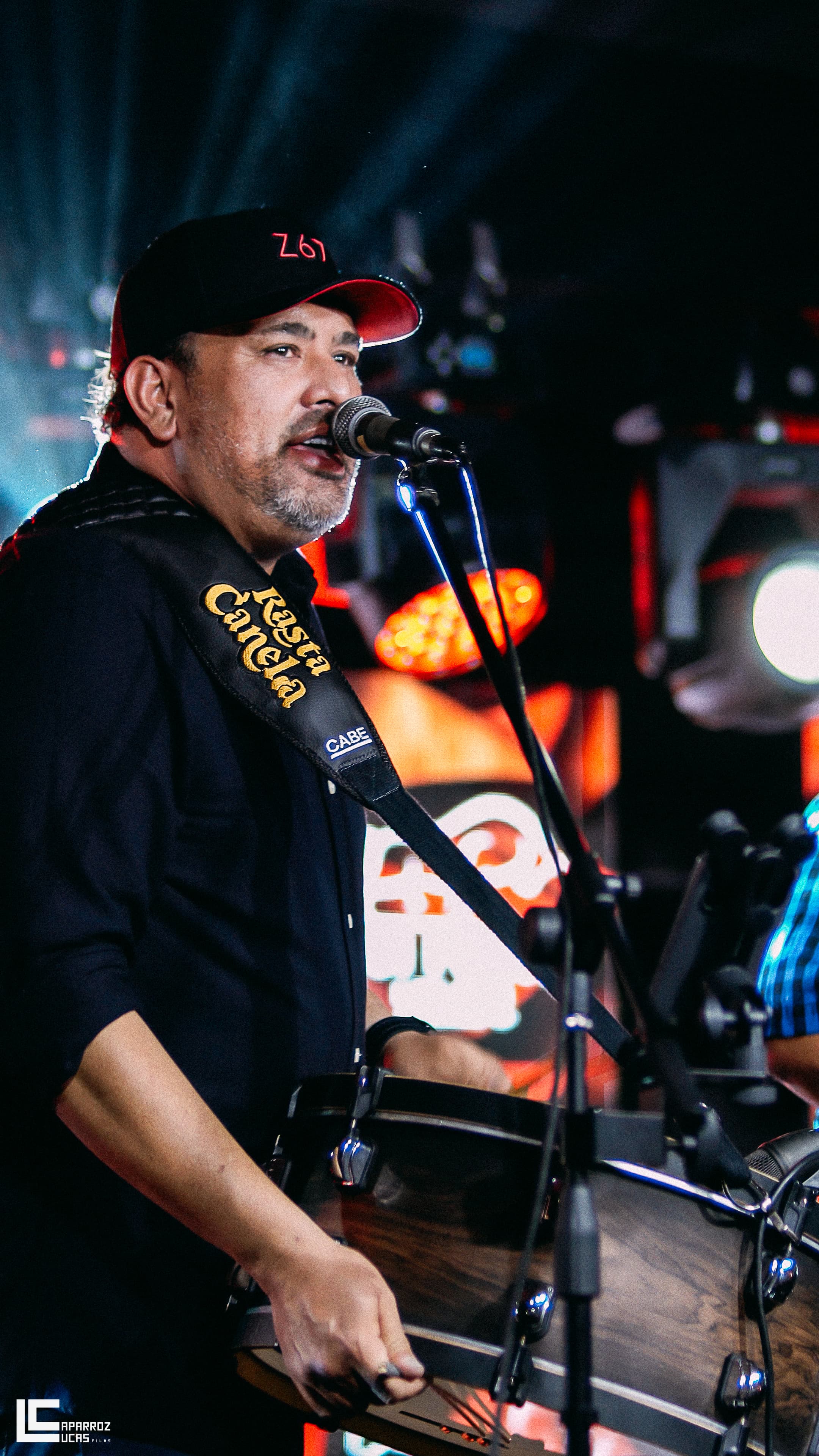 Rafael tocando triângulo e cantando no palco